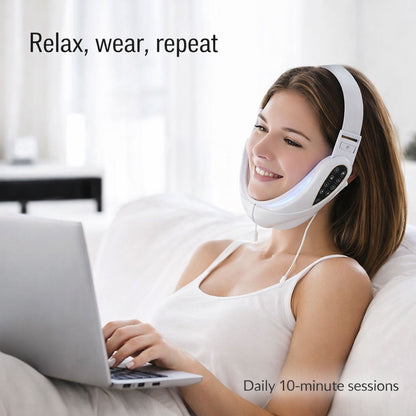 Woman using a white neck device with headphones, sitting on a couch with a laptop.