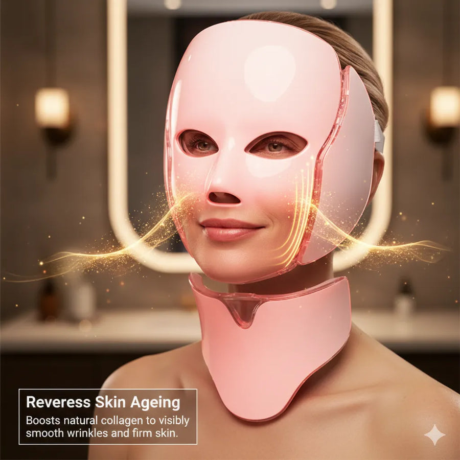 Woman wearing a pink LED face and neck mask in a bathroom setting.