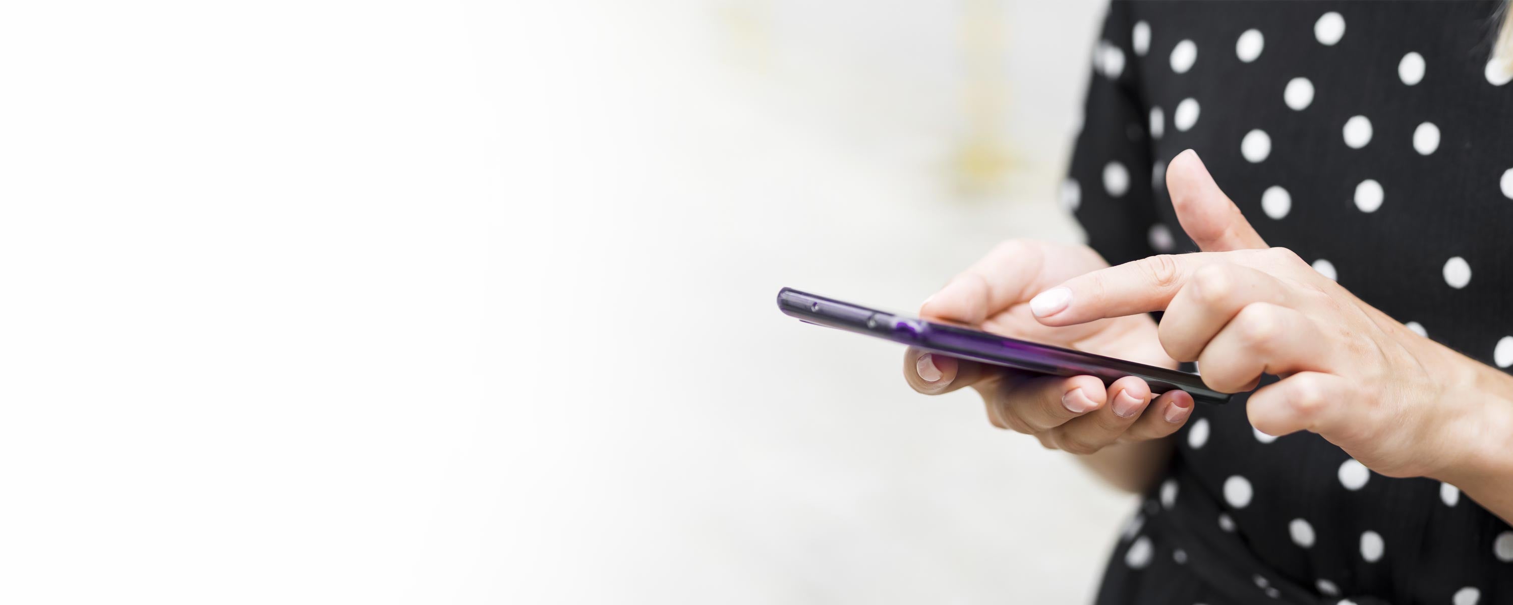 Close-up of a woman's hand using her phone to track a BeautyEssence order.